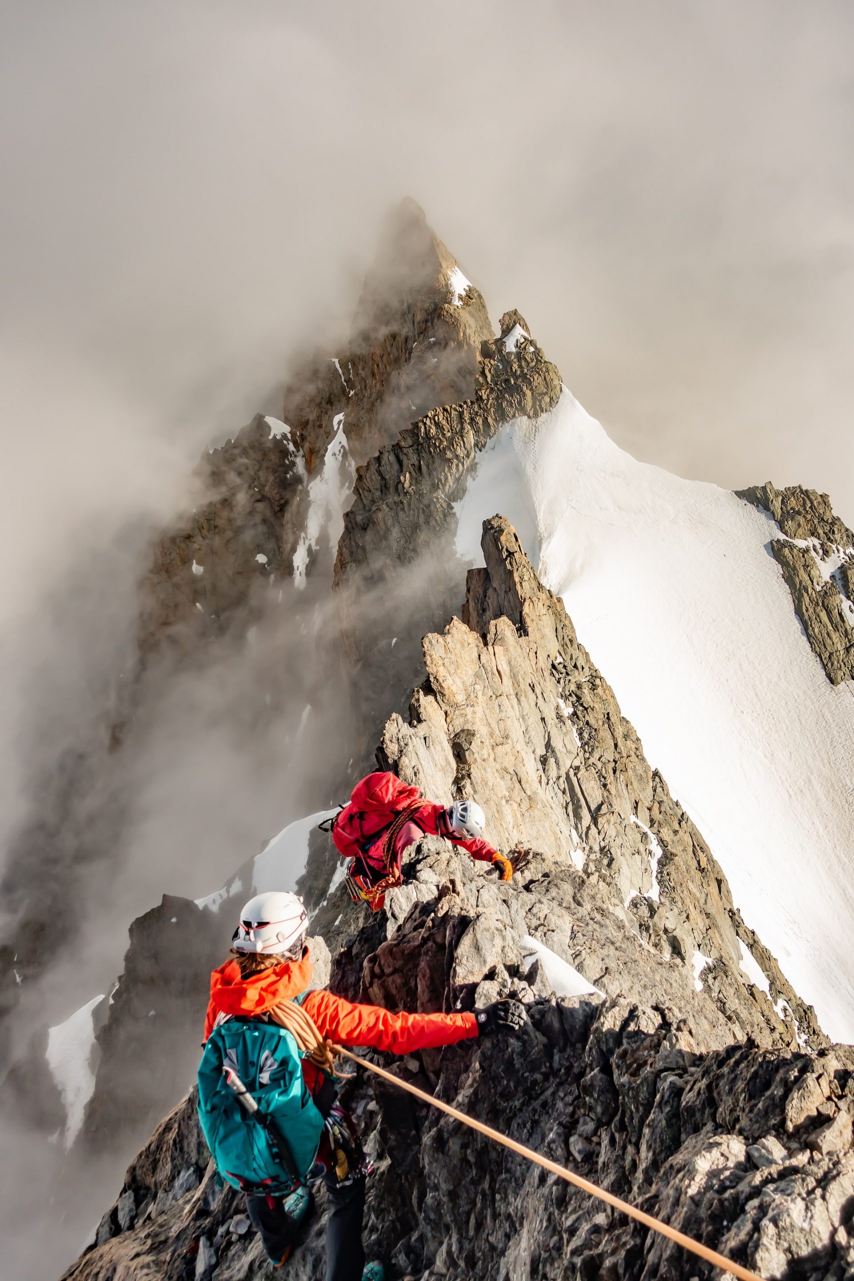 Ein Bild, das den Aufstieg auf einem steilen Bergkamm zeigt. Der Vorausgehende sichert die nachfolgenden Personen.